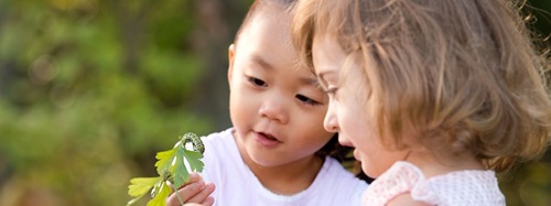 two children watching a caterpillar