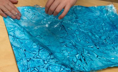 hands peeling plastic wrap off paper