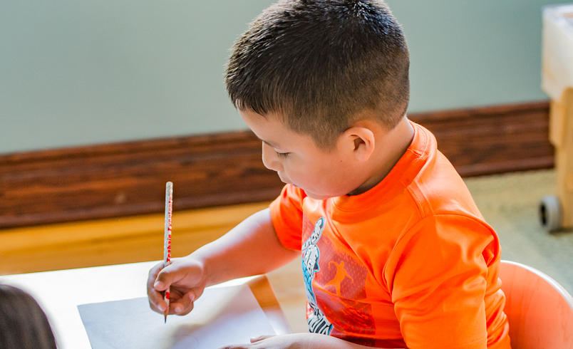 preschool boy writing at a desk
