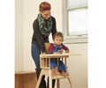 A teacher is helping a child into a high chair