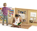 Two children in front of a bulletin panel connected to a book display shelf