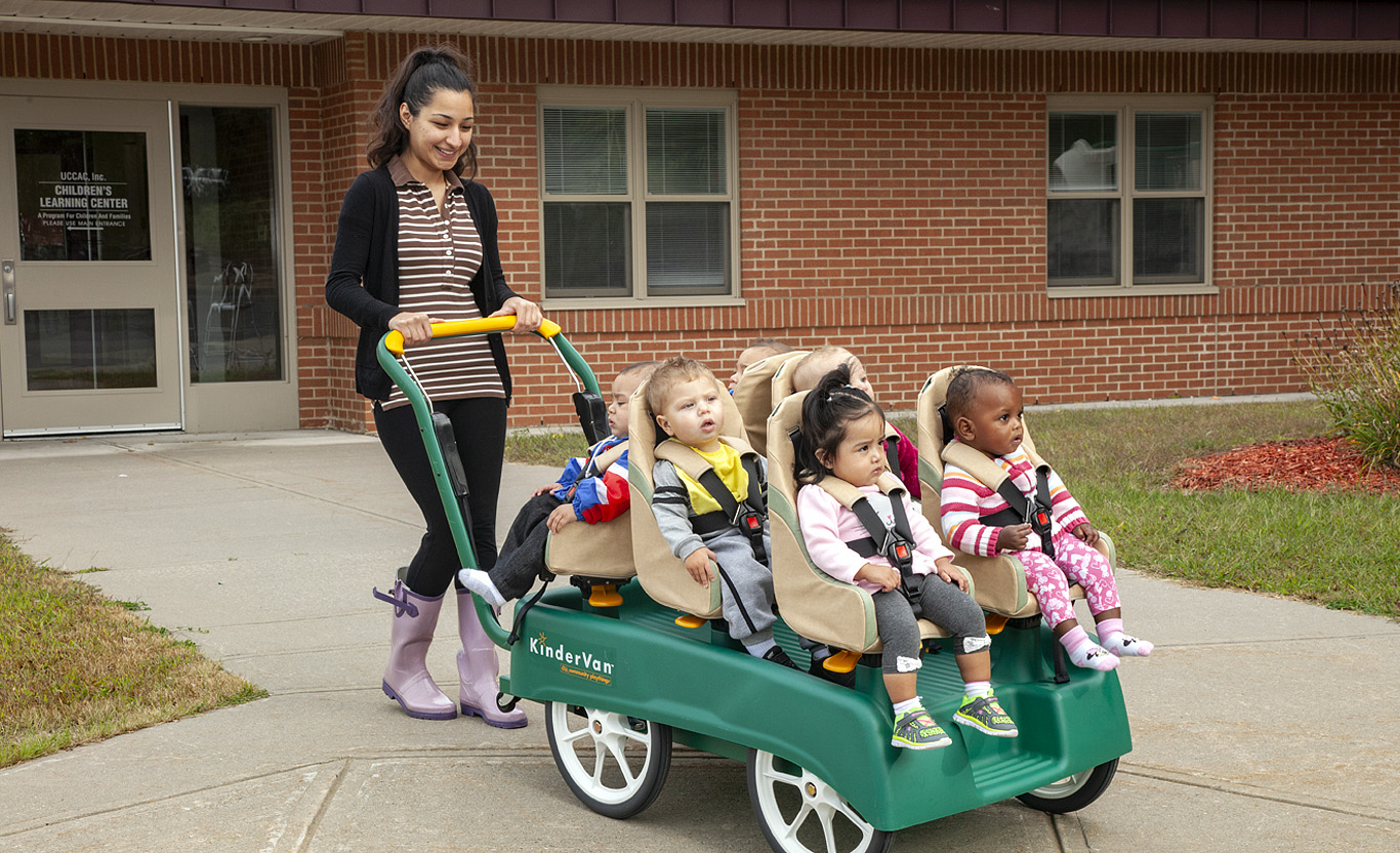 A teacher pushing children in a Kindervan Stroller