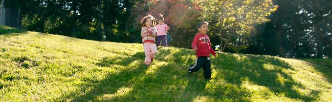 Three children running down a sunny meadow
