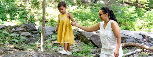 teacher helping a child balance on a log