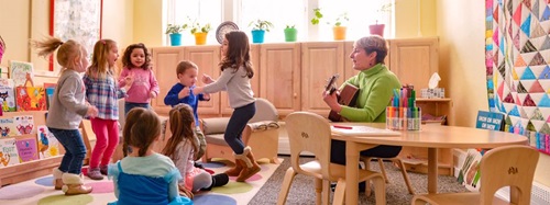 teacher playing guitar to children