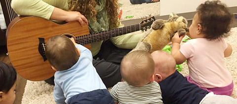 teacher playing guitar to children