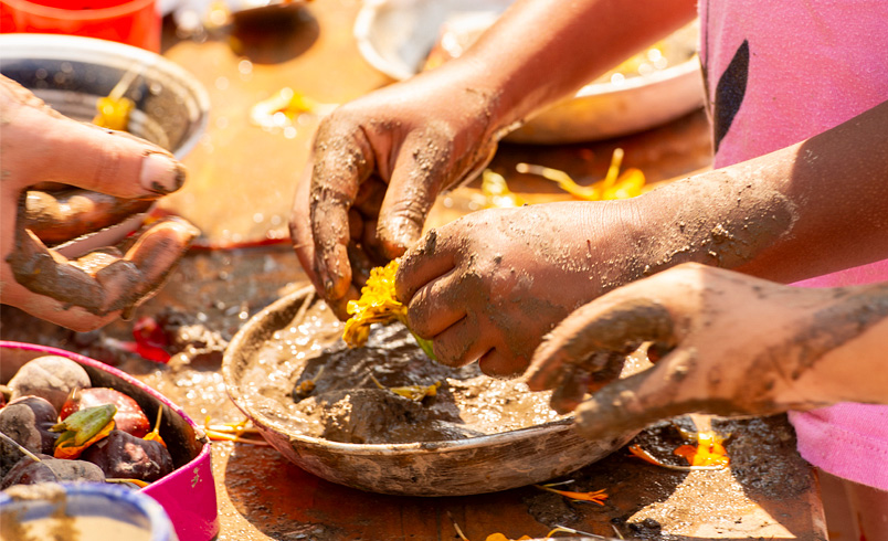 Close up children's hands playing with flowers and mud