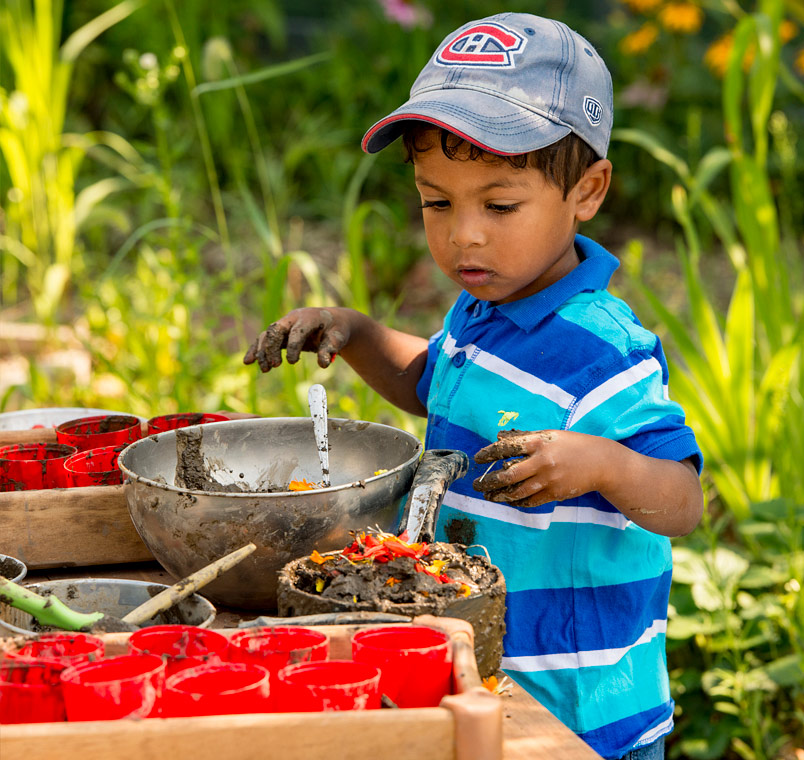 Child playing with mud and flowers