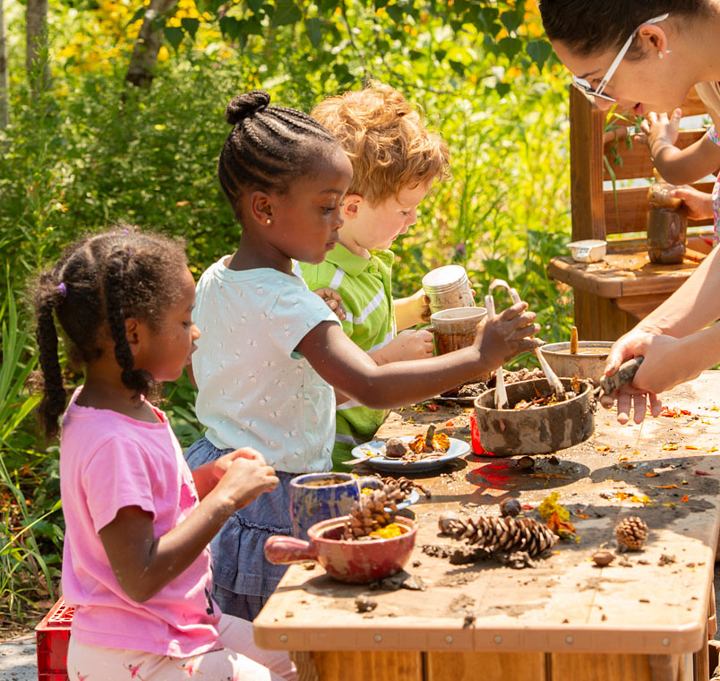 Three children playing with mud kitchen