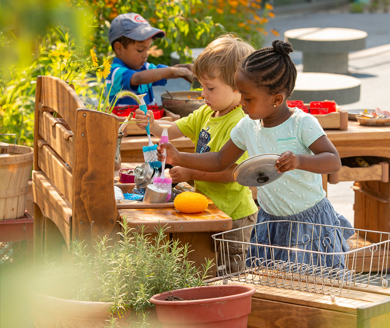 Children washing utensils at mud kitchen