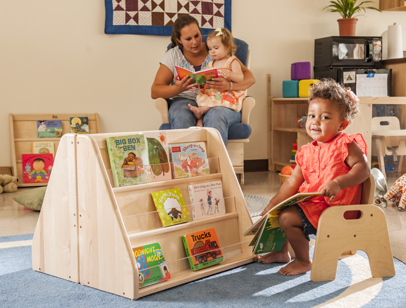 A toddler at a toddler book shelf