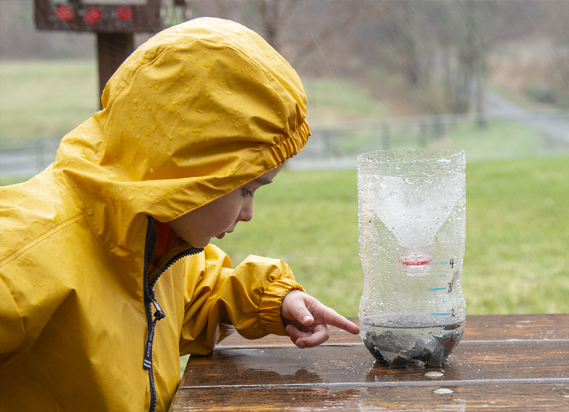 Child looking at DIY rain gauge