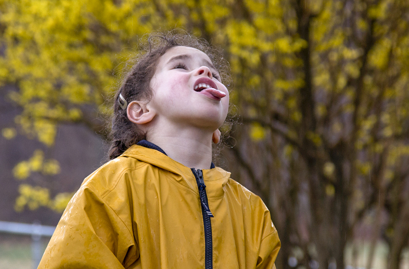 Child catching raindrops on tongue