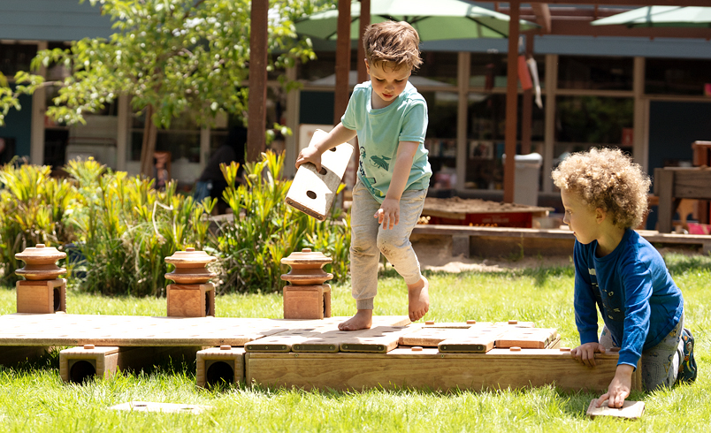 boys playing with outdoor wooden building blocks