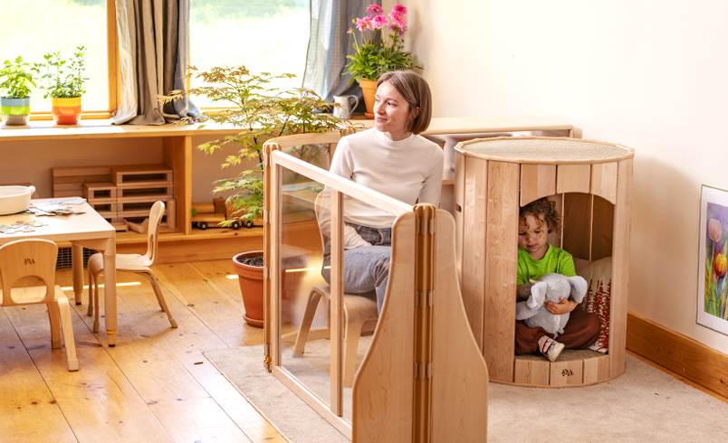 A child in a Calm Nest, with a teacher sitting next to them