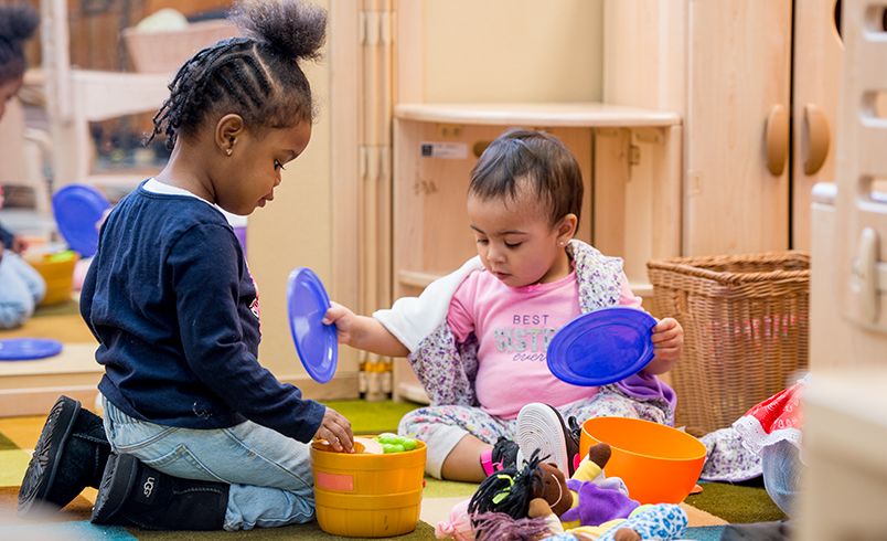Two children playing with doll size dishes in dramatic play center