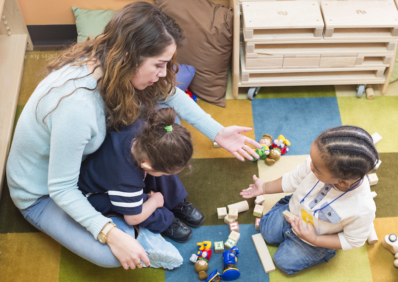 A teacher playing with toddlers on the floor