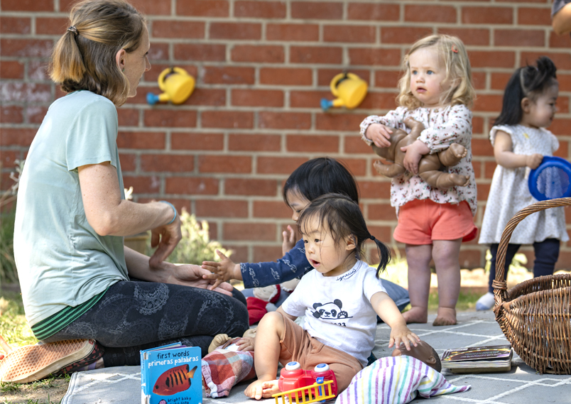 A teacher playing with a number of children outside.