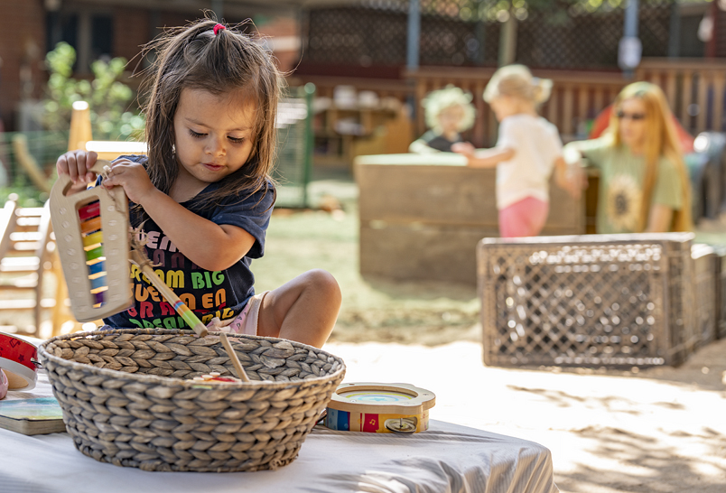 A child playing with a basket outdoor in a sandbox