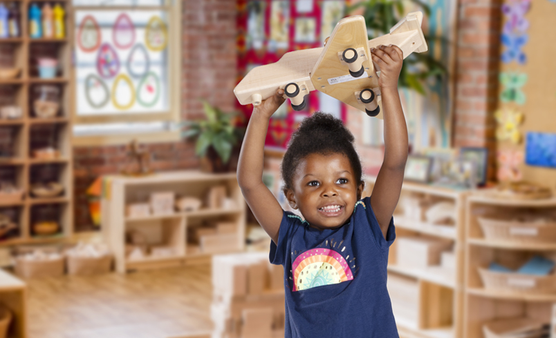 A girl playing with a Community Playthings wooden plane.
