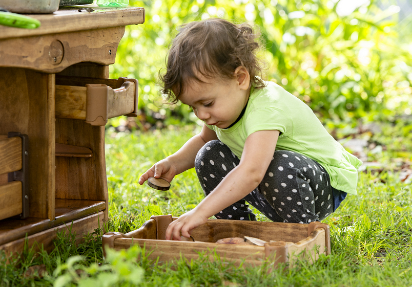 A child playing with a mud kitchen nature tray