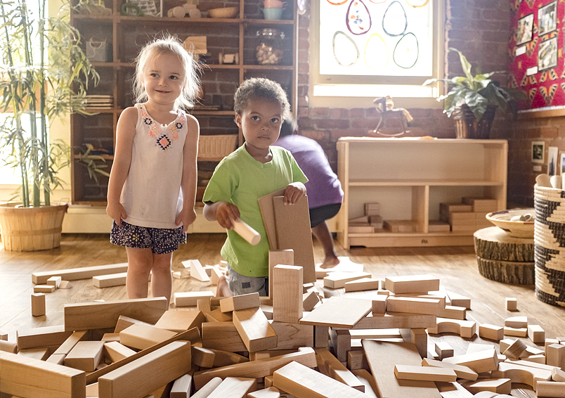 Two children with a knocked down block tower