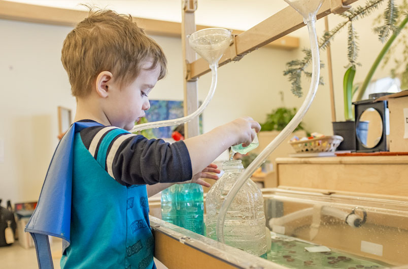 A child playing with water in a Community Playthings Sensory Table