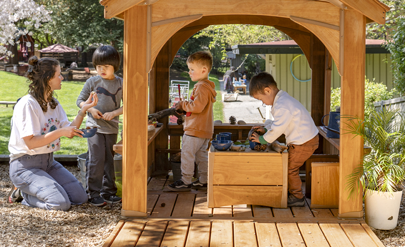 A teacher and children playing with an Outlast Playhouse