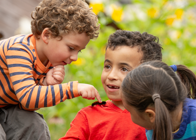 A child looking at a caterpillar on his friends shoulder
