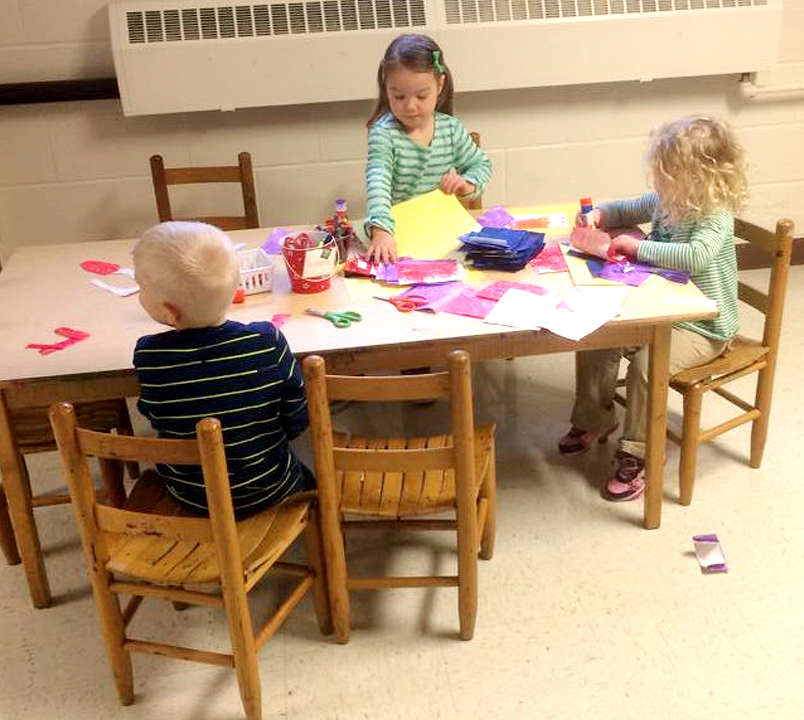 Children working on an art project seated on old chairs