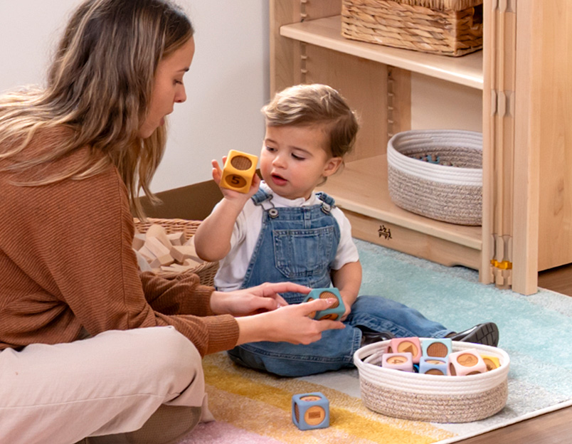 Toddler looking at toys with teacher