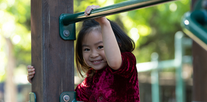 Child laughing from playground structure where she is playing.