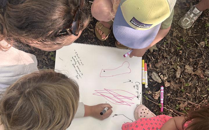 Children gathered around a floor book, drawing