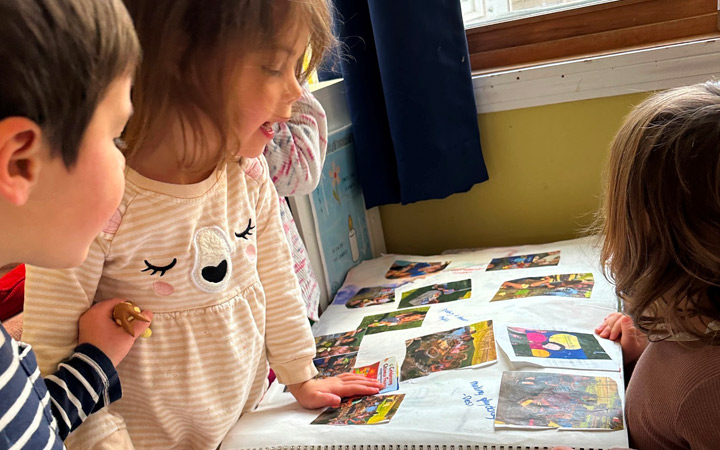 Children looking through their Floorbooks - scrap books of their past year.