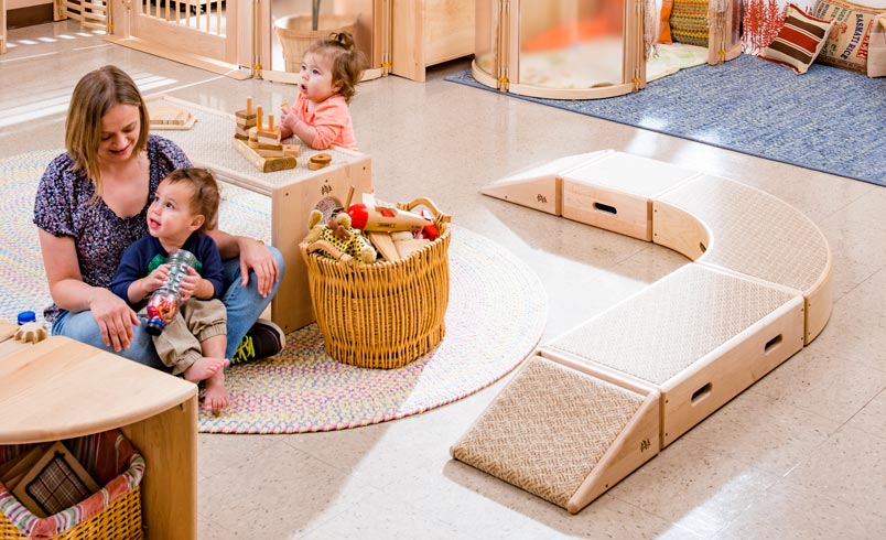 Teacher seated on the floor engaged with Infants
