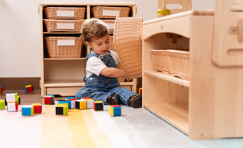 Toddler playing with items on low shelf