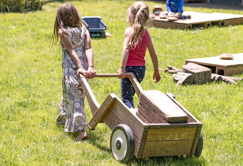 Two chlildren hauling Outlast Planks in Outlast Wheelbarrow