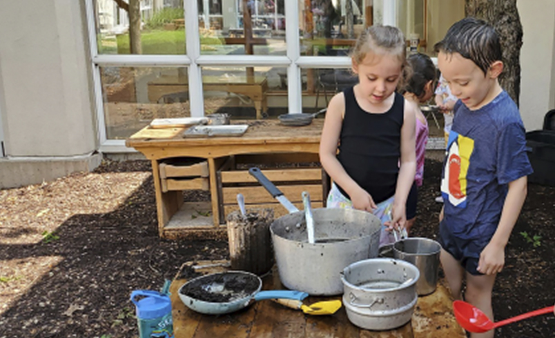 Two children playing at an Outlast Table in Mud Kitchen area
