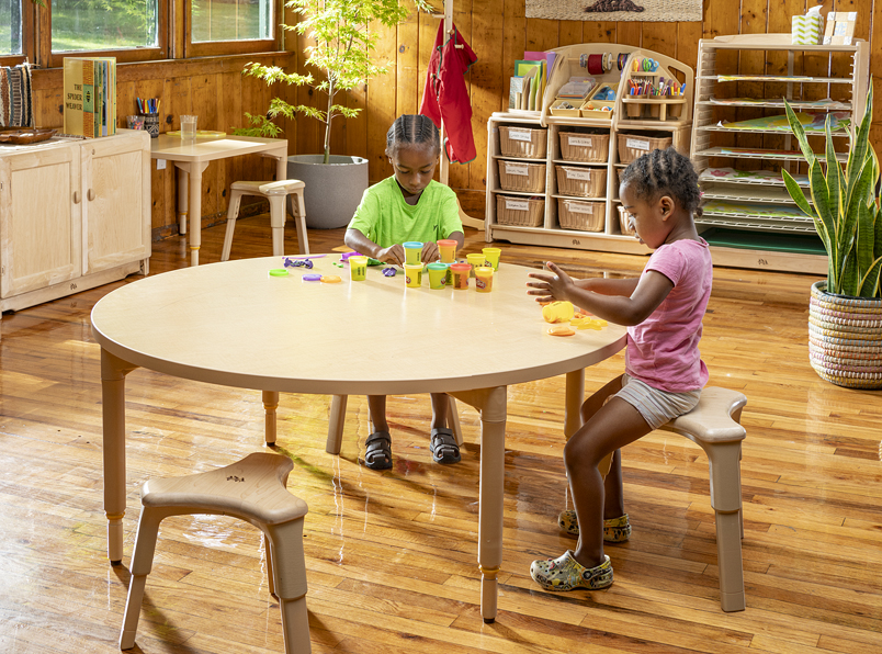 Children working at a table while seated on Grow Right stools