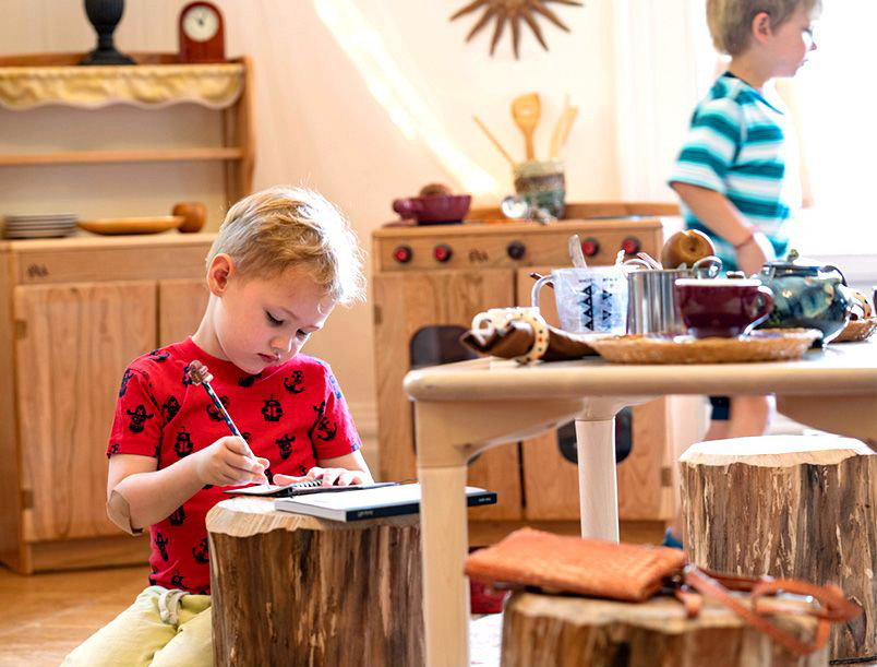 child writing in dramatic play corner