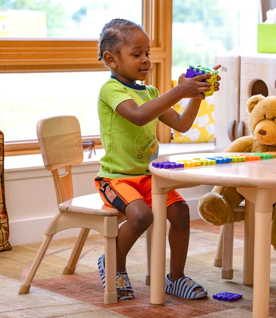 Child seated with upright posture on classroom chair.