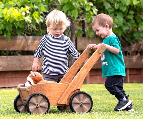Two Children pushing the Outlast Push Wagon with a stuffed animal in it