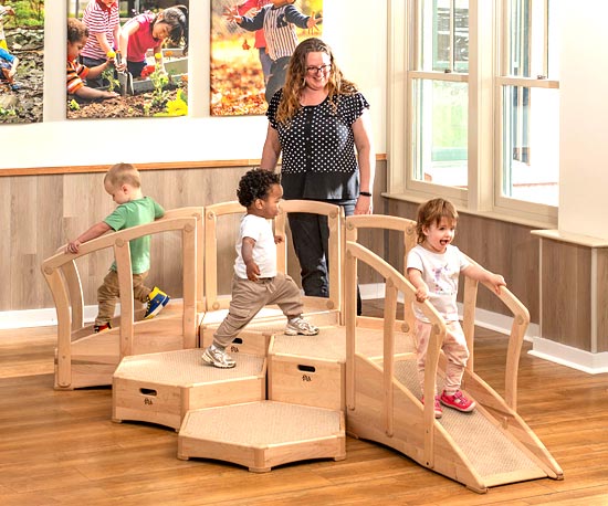 Children engaged in large motor activity on the Toddler Climber while staff member observes.