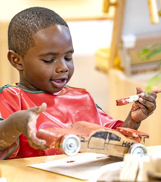 A boy painting a self-made wooden car
