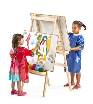 Two children with aprons painting at an easel