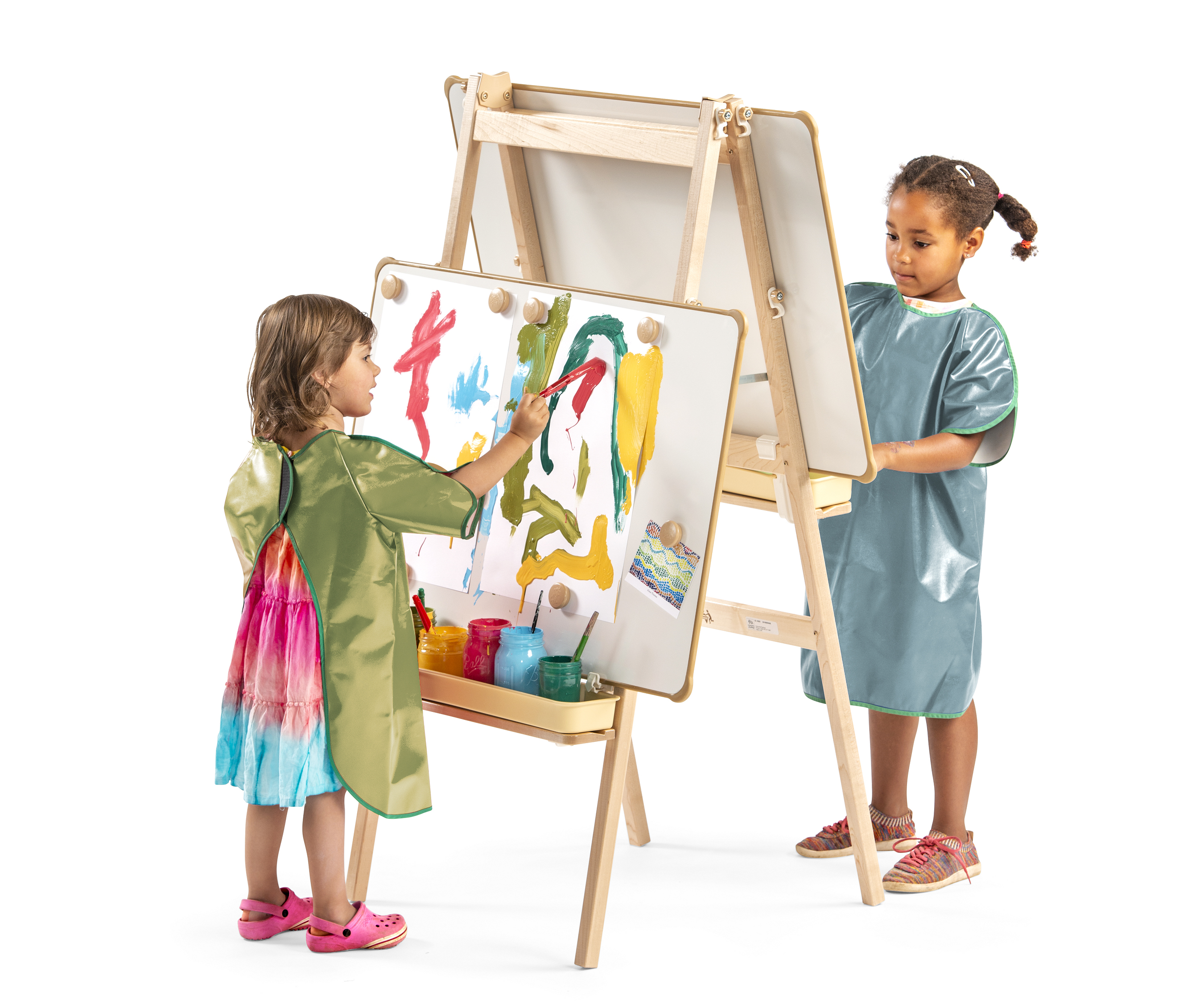 Two children with aprons are using an easel