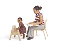 A teacher is sitting on a Teacher Low Chair and a small child is climbing onto a toddler chair