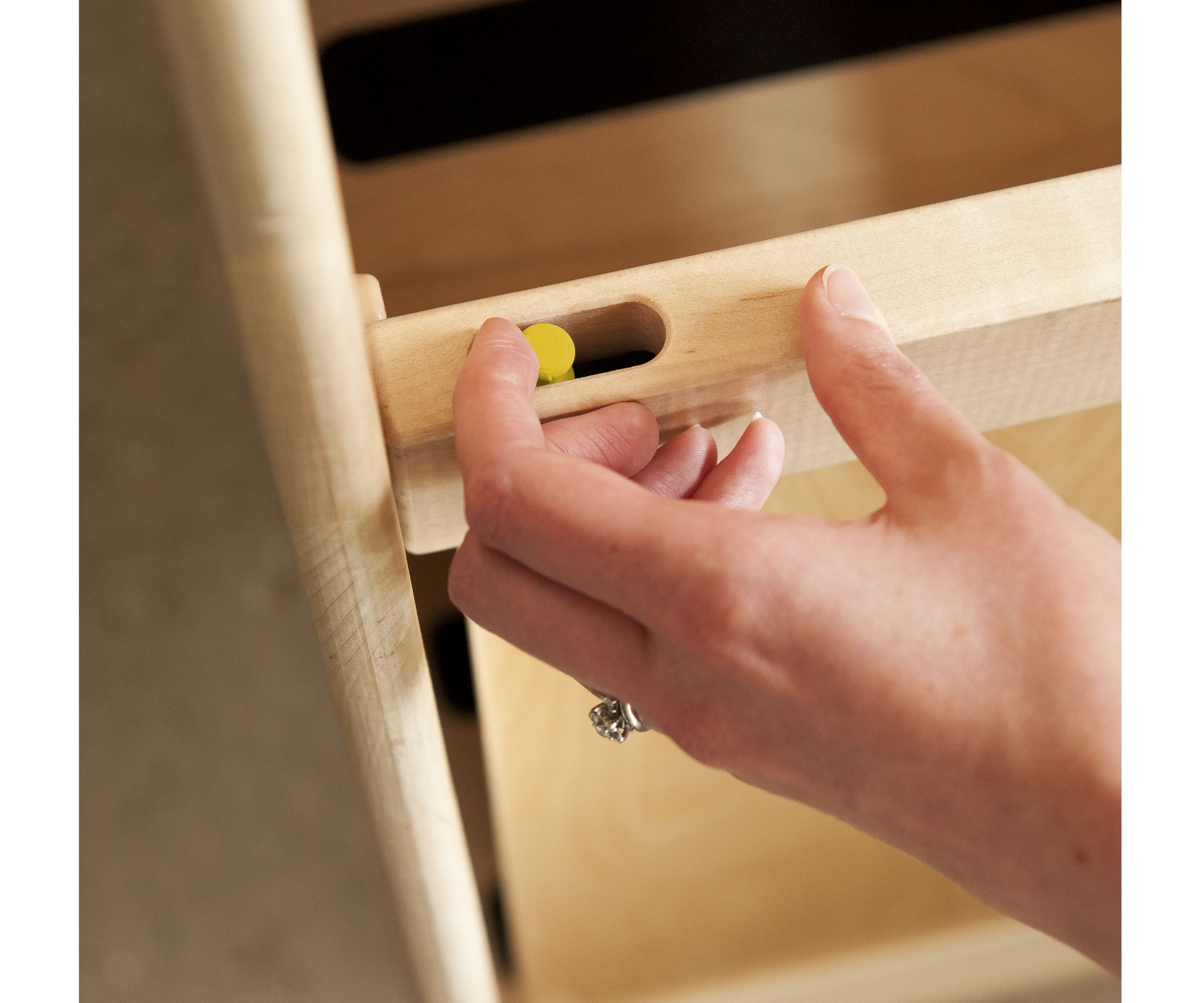 A hand adjusts the height of the Toddler Step Stool by pressing a yellow button.