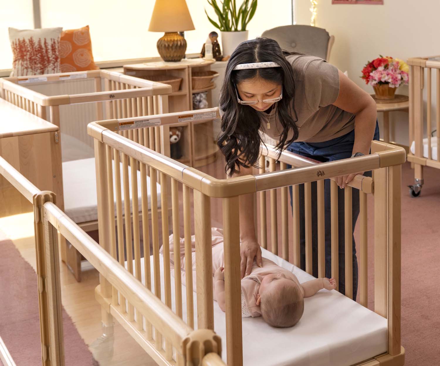 An infant teacher looking at a sleeping baby