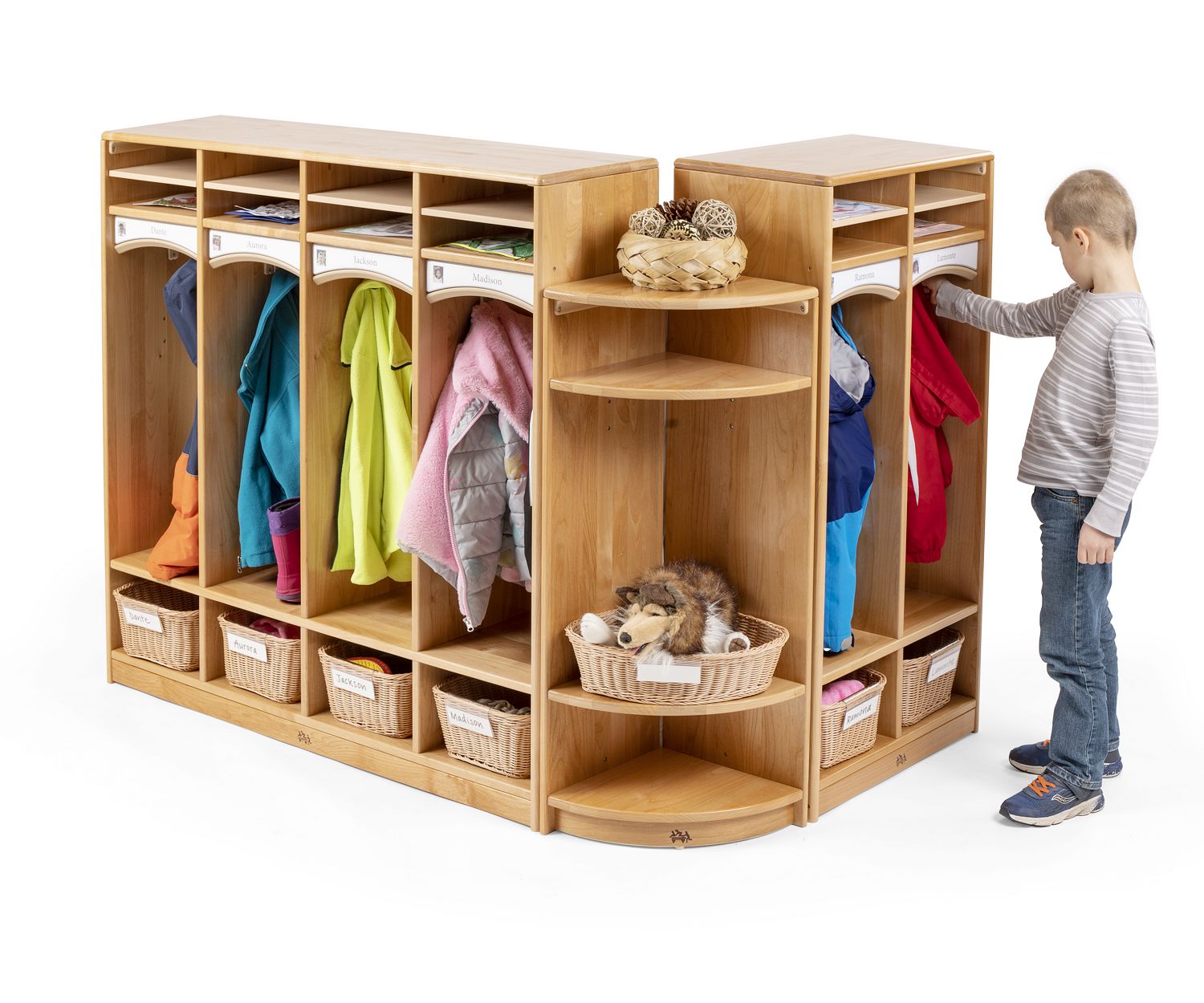 A boy is standing in front of two kindergarten cubbies connected with a Cubby Corner Shelf